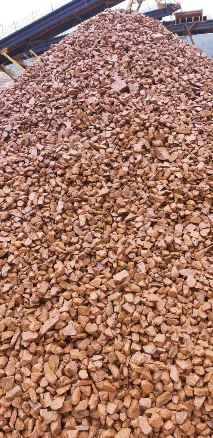 Alto cumulo di frammenti rossastri di bauxite vicino ai nastri trasportatori