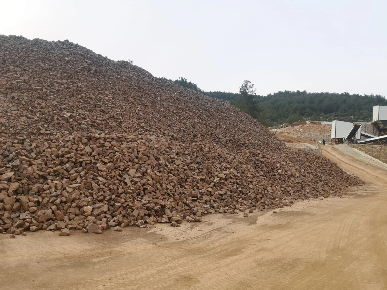 Cumuli di bauxite nel piazzale di carico con alberi sullo sfondo